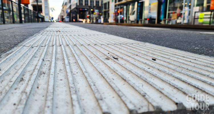 Foto di un dettaglio di un marciapiede di Berlino con le mattonelle striate per le persone ipovedenti.
