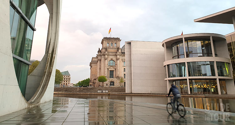 Un cittadino tedesco passa in bici fra i palazzi del potere politico della Germania, lungo il fiume Sprea a Berlino.