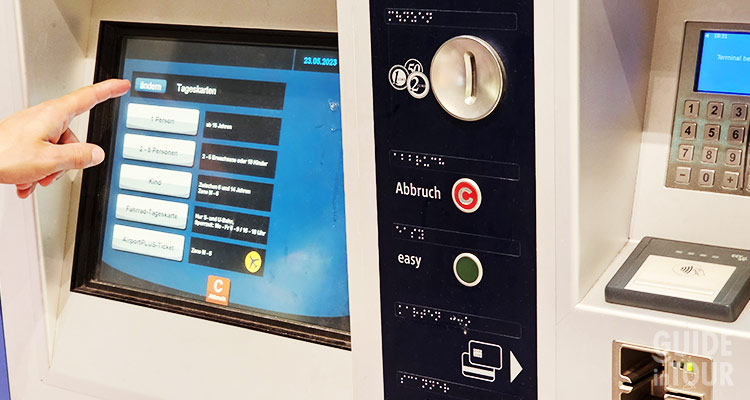 Una persona aquistando alle macchinette alcuni baglietti dei mezzi pubblici di Monaco di Baviera.